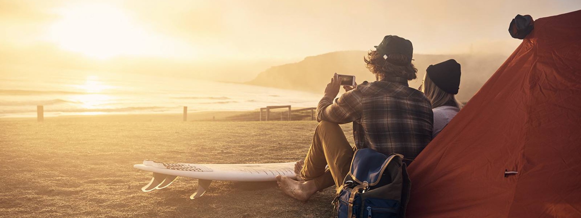 two people sitting on a beach and watching at a sunset