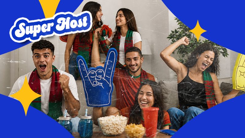 A lively group of five people wearing scarves, cheering with excitement. Popcorn and drinks on the table, "SuperHost" logo in the top left, emphasizing hosting.